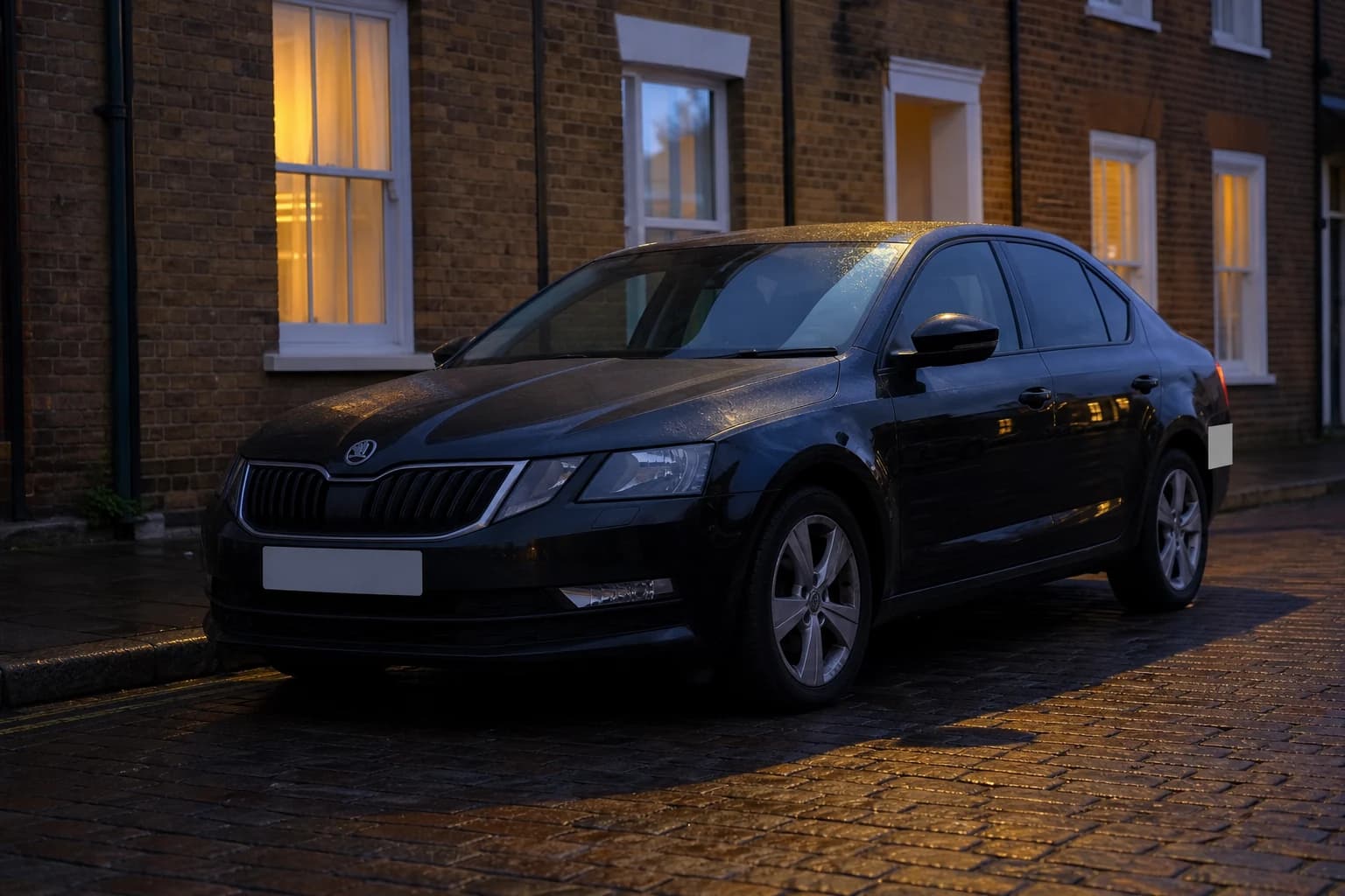Dark saloon parked beside brick houses at dusk
