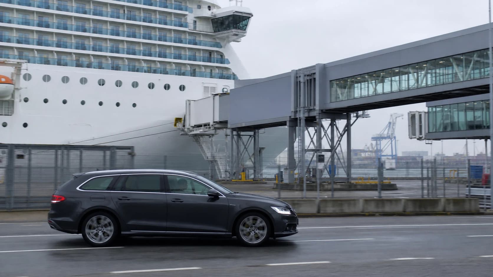 Estate car passing a cruise ship and boarding bridge